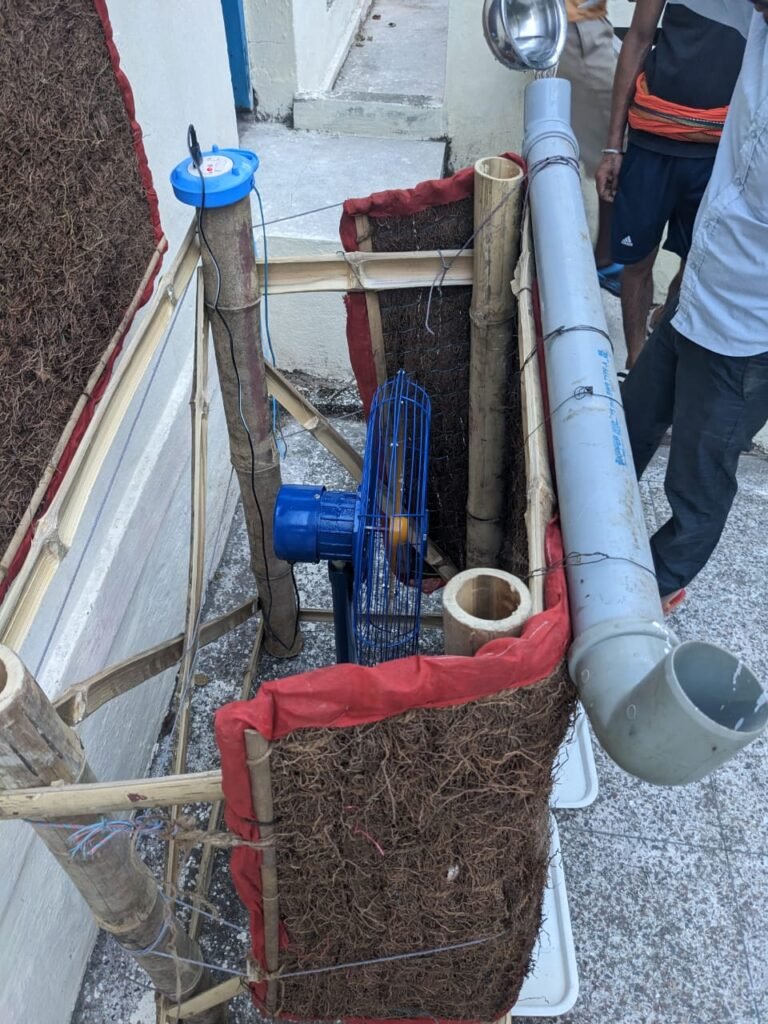 Inside view of the DIY air cooler showing the PVC drip pipe, water pump, and Khus grass arrangement